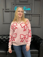 pink bow sweater, holiday sweater, girly knit top, cozy winter sweater, red and pink sweater, boutique knitwear, bow print top, women’s boutique sweater, cute holiday outfit, cozy chic sweater