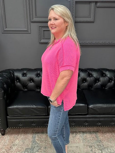 Woman in a pink shirt and jeans standing in front of a black leather couch.