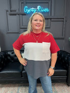 Woman wearing a red, white, and gray shirt with a black leather couch and 'Gypsy River' neon sign in the background.