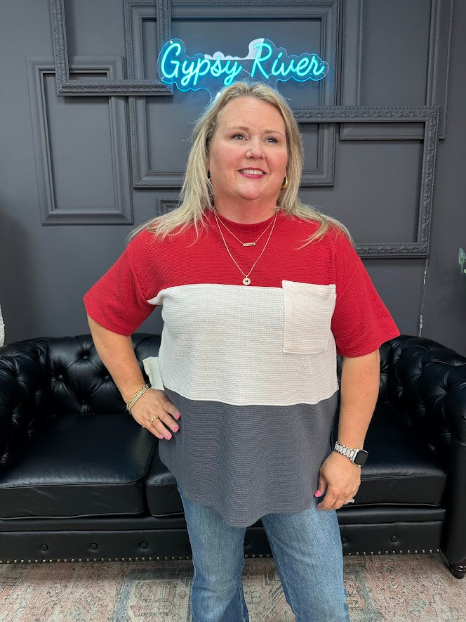 Woman wearing a red, white, and gray shirt with a black leather couch and 'Gypsy River' neon sign in the background.