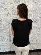 Liverpool black sleeveless blouse with ruffle trim and tie front neckline on model