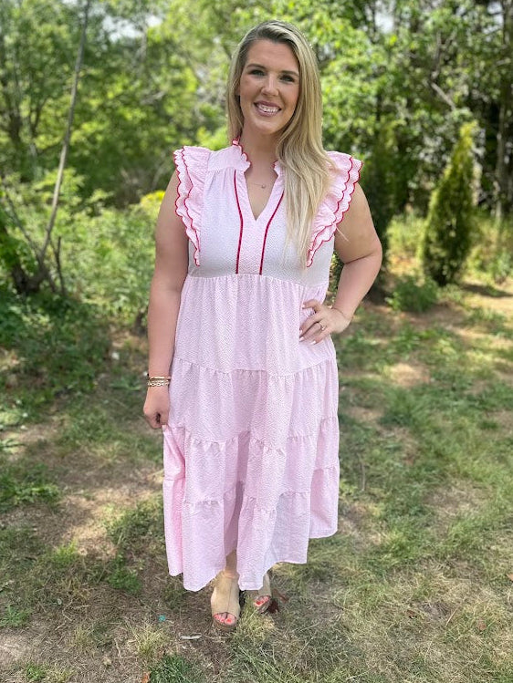 Woman in a pink dress standing outdoors with greenery in the background