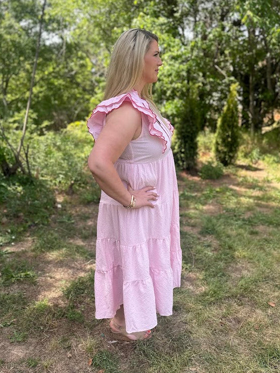 Woman in a pink dress standing outdoors in a natural setting