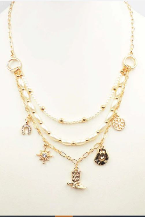 Gold layered necklace with various charms on a white background
